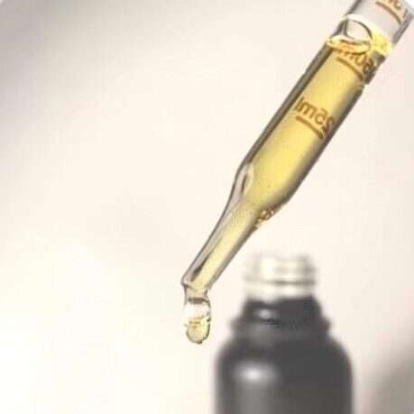 Image of golden CBD oil in dropper with bottle in background